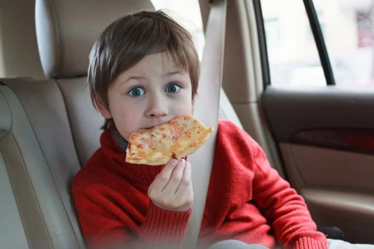 child eating pizza in car